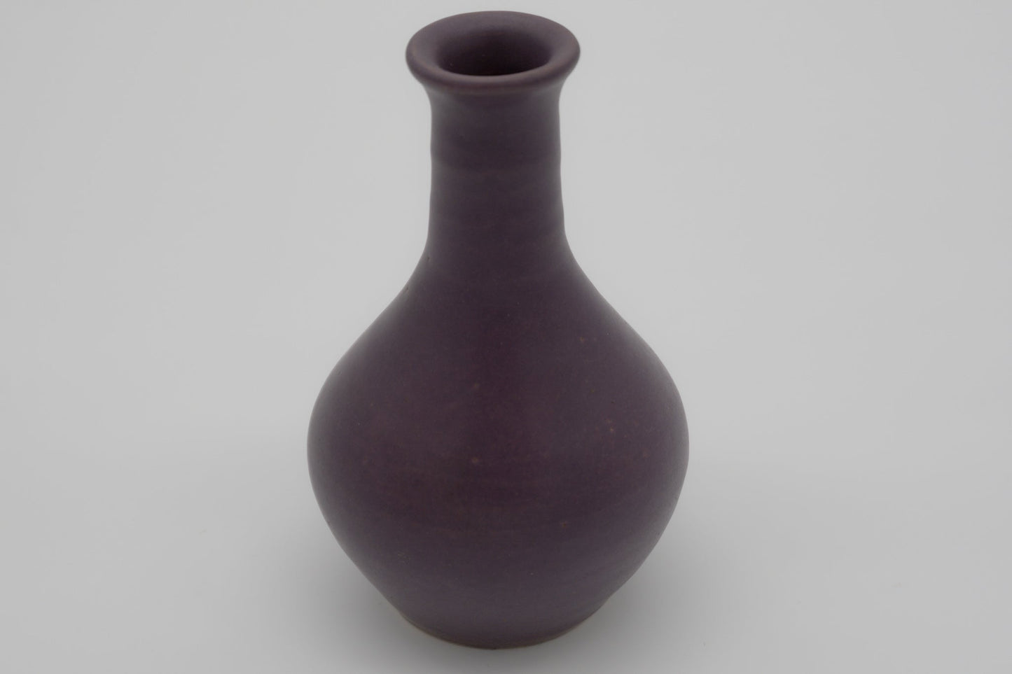 Small purple glazed pottery vase with semi-cylindrical neck and narrow opening, marked on the bottom.