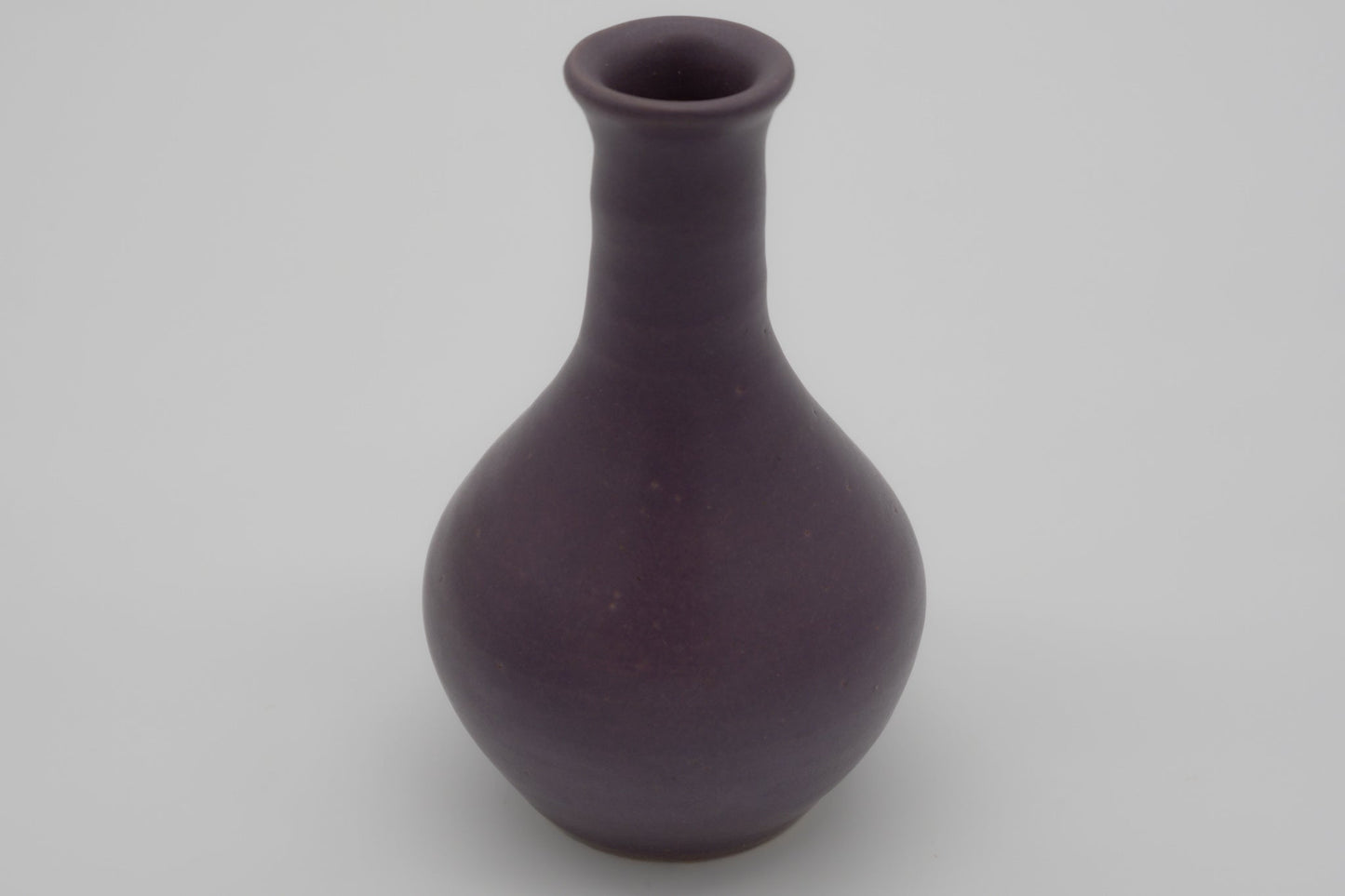 Small purple glazed pottery vase with semi-cylindrical neck and center choke, marked on the bottom.