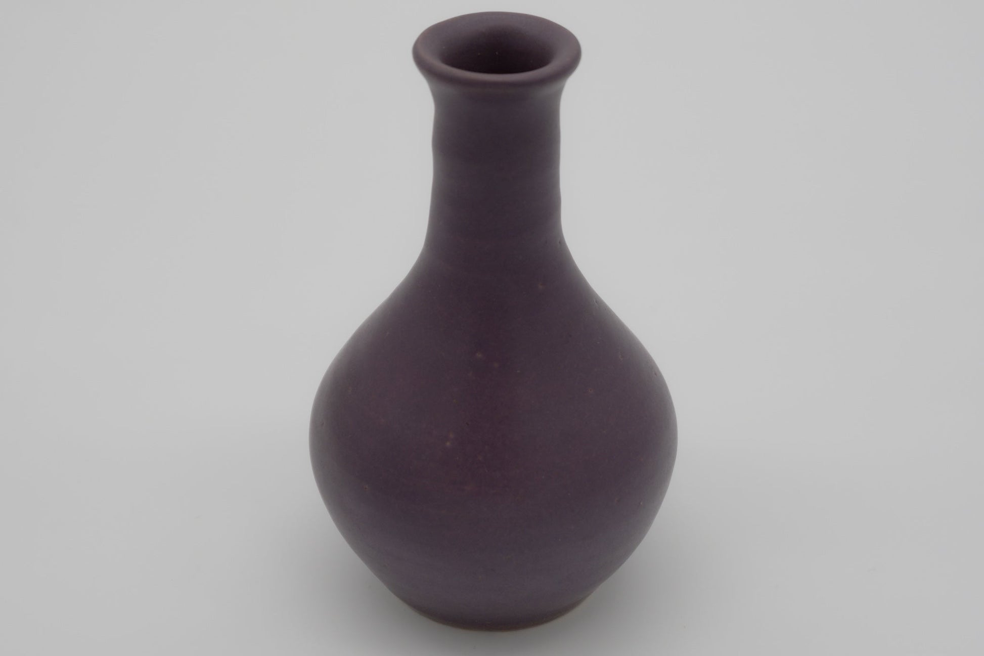 Small purple glazed pottery vase with semi-cylindrical neck and center choke, marked on the bottom.