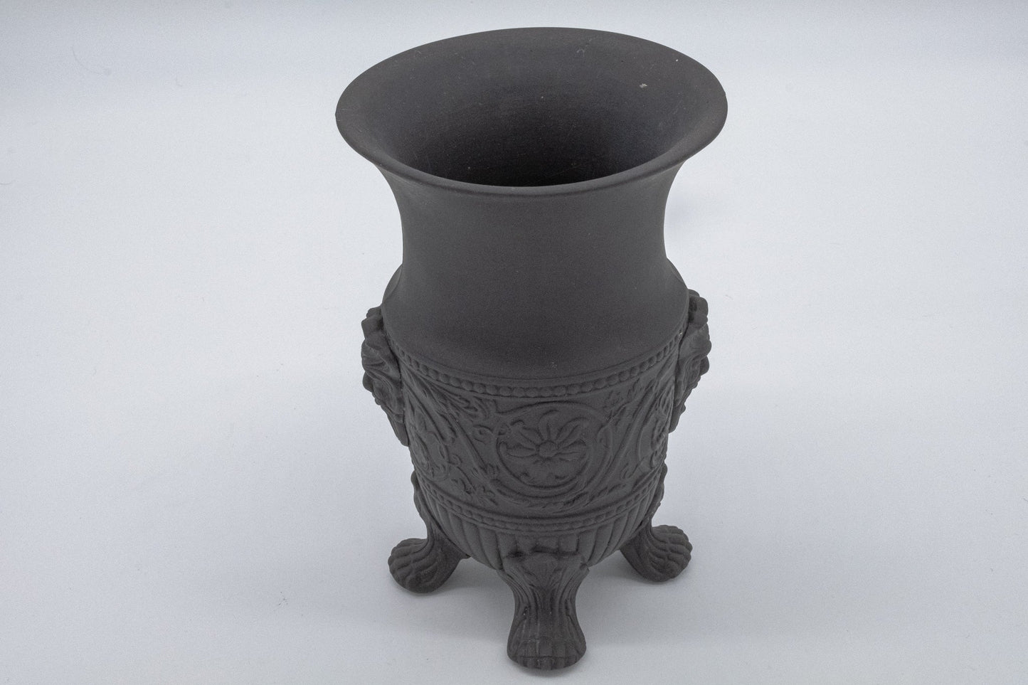 Wedgwood solid black basalt vase with Greek god portraits and intricate carvings on tripod feet.